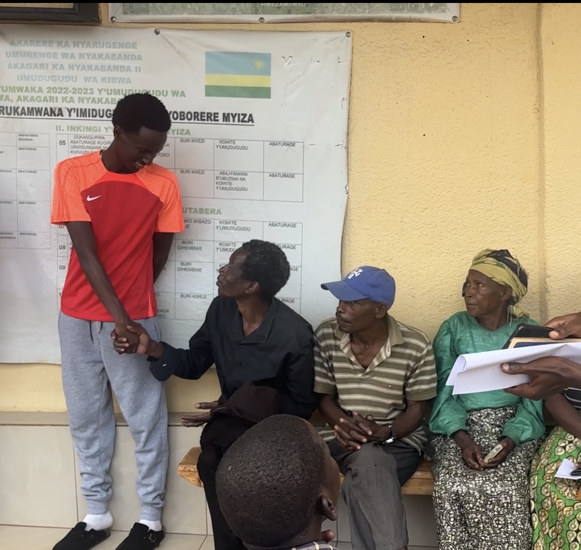 A young man greeting a seated community member
